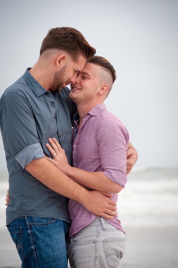 Gay men embracing on a beach.