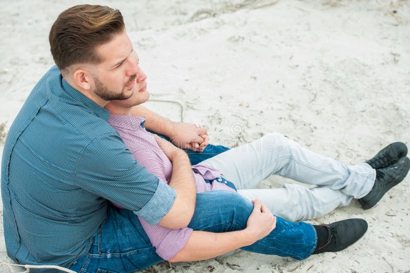 Gay men embracing on a beach. 