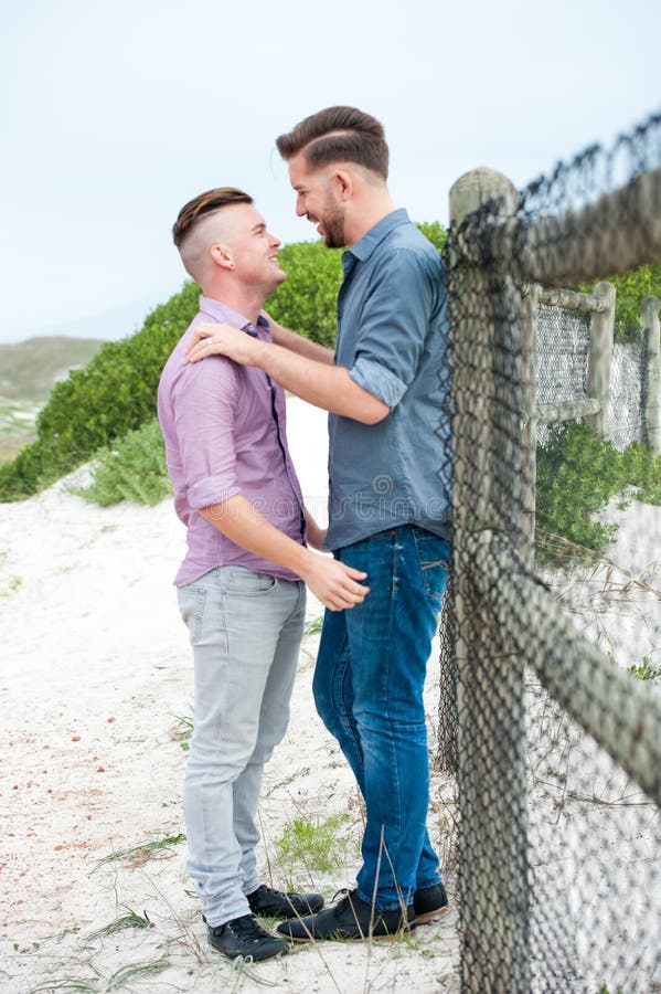 Gay men embracing on a fence. 