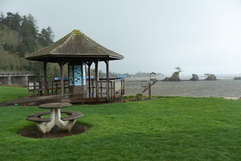 A gazebo on the lush green lakeshore in Siletz Bay Park in Oregon, USA