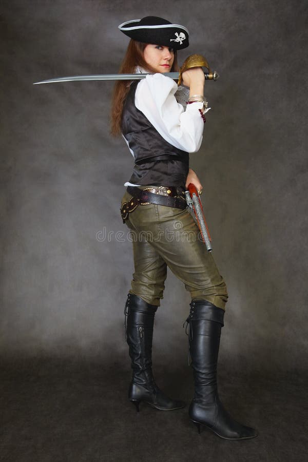 Woman dressed as a pirate standing on a black background with a sword. Woman dressed as a pirate standing on a black background with a sword