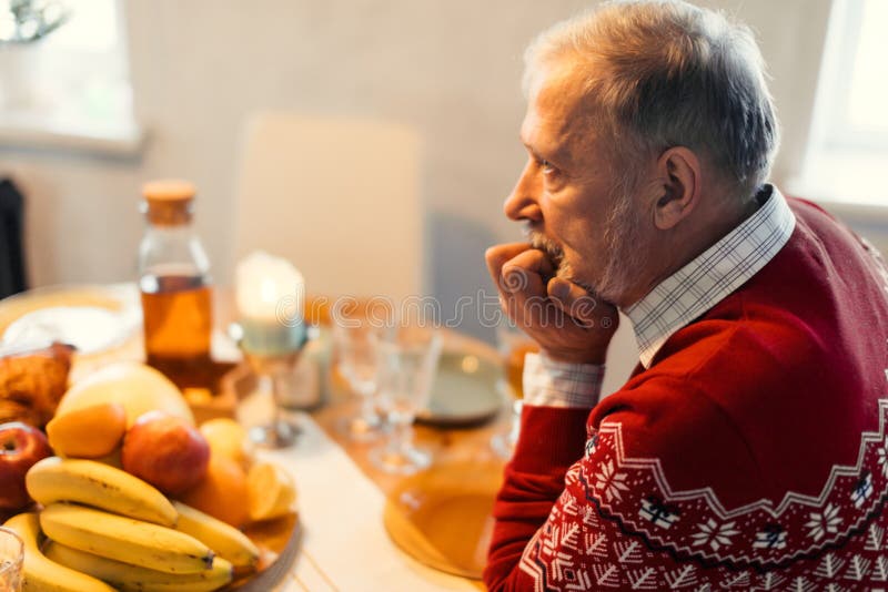 Gealterter deprimierter besorgter Mann, der allein in der Küche sitzt