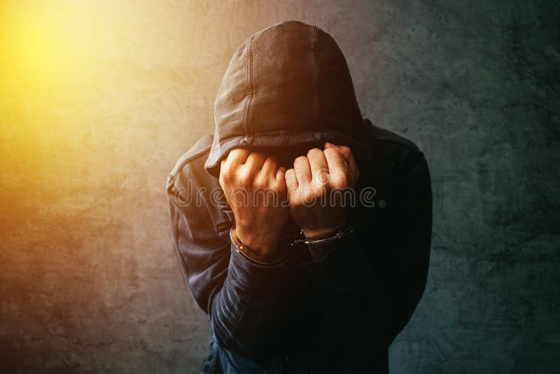 Gearresteerde computerhakker met handcuffs die jasje met een kap dragen royalty-vrije stock fotografie Gearresteerde computerhakker met handcuffs die jasje met een kap dragen royalty-vrije stock fotografie