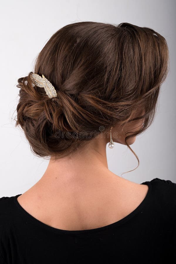 Geassembleerd formeel kapsel donker die haar met de kam in de vorm van bladeren wordt verfraaid, zijaanzicht stock fotografie Geassembleerd formeel kapsel donker die haar met de kam in de vorm van bladeren wordt verfraaid, zijaanzicht stock fotografie