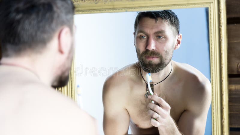 Gebaarde mens die zijn tanden voor spiegel in badkamers borstelen royalty-vrije stock foto's Gebaarde mens die zijn tanden voor spiegel in badkamers borstelen royalty-vrije stock foto's