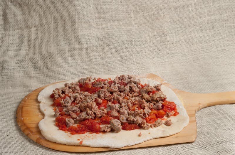 Gebackene selbst gemachte Pizza, ausgebreitete organische zerquetschte Tomaten und heiße italienische Wurst über bereitgestelltem lizenzfreies stockfoto Gebackene selbst gemachte Pizza, ausgebreitete organische zerquetschte Tomaten und heiße italienische Wurst über bereitgestelltem lizenzfreies stockfoto