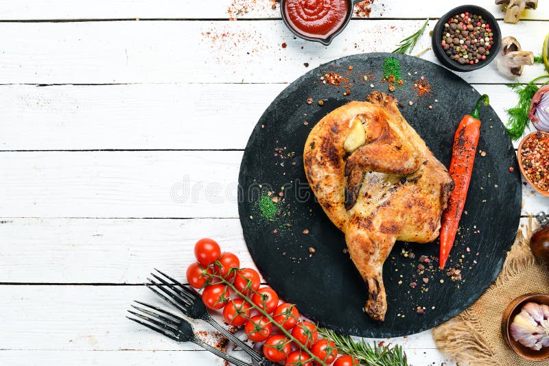 Gebackene Wachteln, Huhn mit Chili Pfeffer auf einer schwarzen Steinplatte oberste Ansicht,. Gebackene Wachteln, Huhn mit Chili Pfeffer auf einer schwarzen Steinplatte Top-Ansicht, freier Platz für Ihren Text Rustikaler Stil
