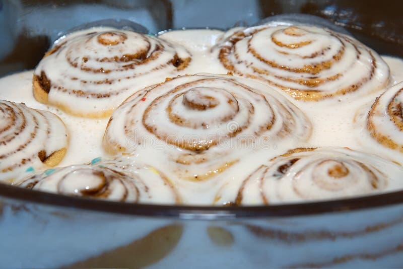 Gebackene Zimtbrötchen wurden vorbei mit einer weißen Zuckerglasur gegossen, um zu tränken lizenzfreies stockbild Gebackene Zimtbrötchen wurden vorbei mit einer weißen Zuckerglasur gegossen, um zu tränken lizenzfreies stockbild
