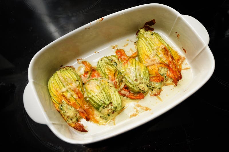 Gebakken courgettebloemen in een braadpanschotel op een donkere achtergrond, royalty-vrije stock foto Gebakken courgettebloemen in een braadpanschotel op een donkere achtergrond, royalty-vrije stock foto