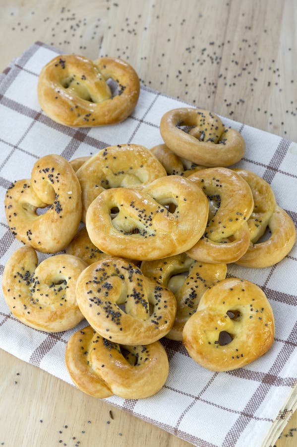 Gebakken verse pretzels op houten lijst aangaande handdoek, hart en verdraaide die knoopvormen, met het zout en de karwijzaden wo royalty-vrije stock afbeelding Gebakken verse pretzels op houten lijst aangaande handdoek, hart en verdraaide die knoopvormen, met het zout en de karwijzaden wo royalty-vrije stock afbeelding