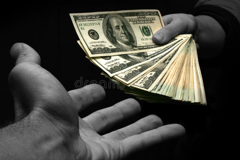 A stack of cash being handed over from one hand to another. A stack of cash being handed over from one hand to another.