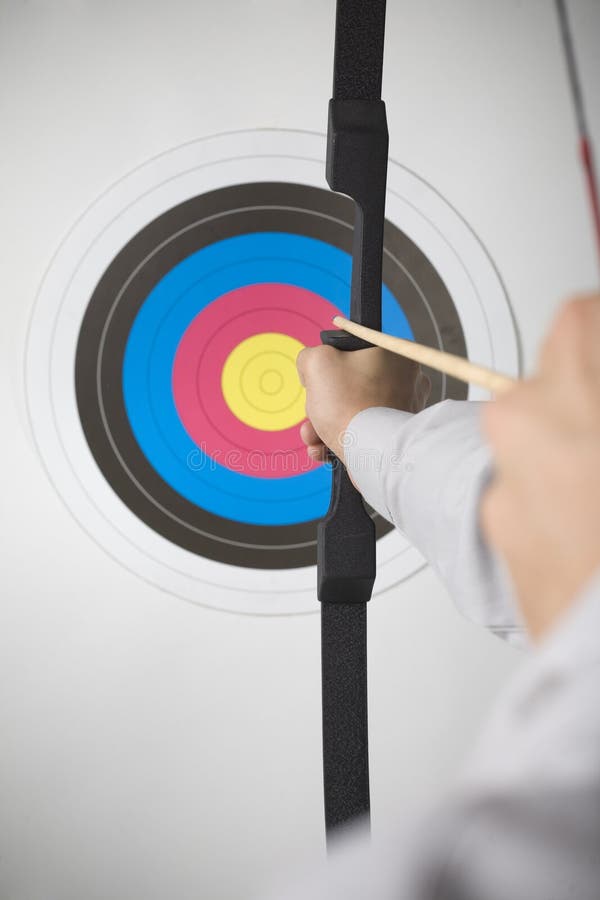 Businessman holding bow and shooting to archery target. Rear view, gray background. Businessman holding bow and shooting to archery target. Rear view, gray background