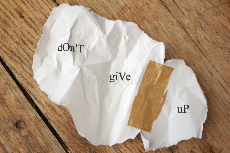 Crumpled piece of torn paper stuck together with tape with the message dont give up. Crumpled piece of torn paper stuck together with tape with the message dont give up