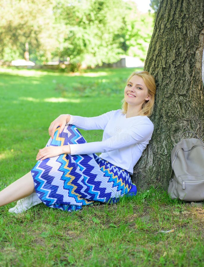 Give yourself break and enjoy leisure. Woman blonde take break relaxing in park. Find peaceful place in park. Girl sit on grass lean on tree trunk relaxing in shadow green nature background. Give yourself break and enjoy leisure. Woman blonde take break relaxing in park. Find peaceful place in park. Girl sit on grass lean on tree trunk relaxing in shadow green nature background.