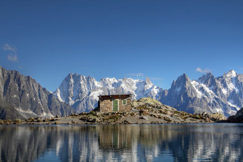 Panorama over the Mont Blanc Massif from the Lake White (Lac Blanc - 2352m), with the Grandes Jorasses (4208m) and Dent du Geant (4013m) behind the building and on the right the several peaks of Aiguilles du Chamonix (3842m). In the foreground the remains of the old shelter on this pitoresque terrace in the Aiguilles Rouges massif above Chamonix valley in France. Panorama over the Mont Blanc Massif from the Lake White (Lac Blanc - 2352m), with the Grandes Jorasses (4208m) and Dent du Geant (4013m) behind the building and on the right the several peaks of Aiguilles du Chamonix (3842m). In the foreground the remains of the old shelter on this pitoresque terrace in the Aiguilles Rouges massif above Chamonix valley in France.