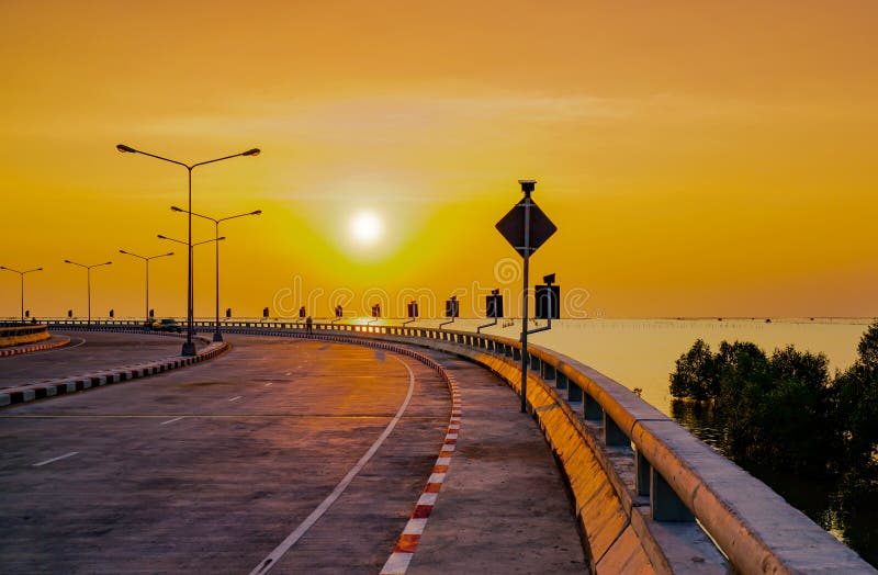 Gebogen kustweg met binnen straatlantaarn en oranje hemel bij zonsondergang stock foto's Gebogen kustweg met binnen straatlantaarn en oranje hemel bij zonsondergang stock foto's