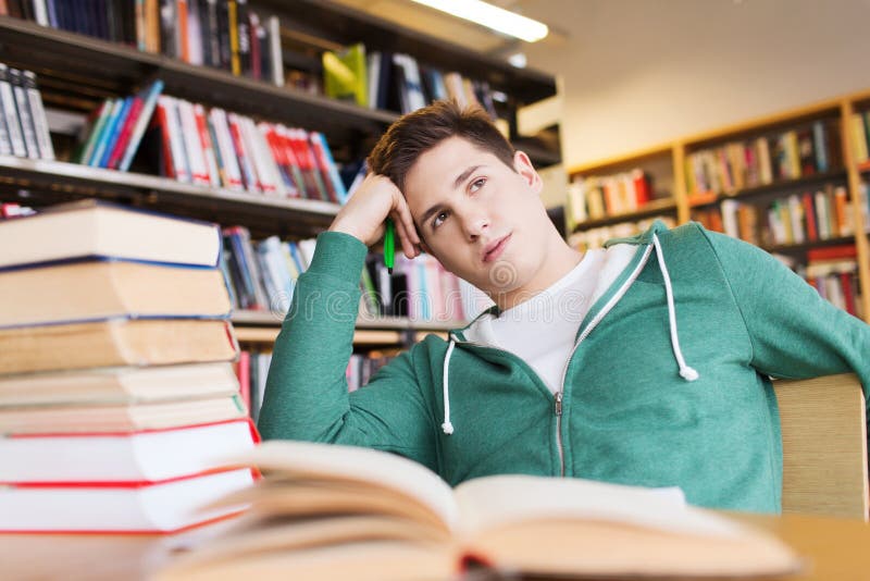 Gebohrter Student oder junger Mann mit Büchern in der Bibliothek lizenzfreies stockfoto Gebohrter Student oder junger Mann mit Büchern in der Bibliothek lizenzfreies stockfoto