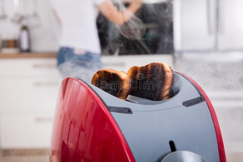 Close-up Of Burnt Toast Coming Out Of Toaster In Kitchen. Close-up Of Burnt Toast Coming Out Of Toaster In Kitchen