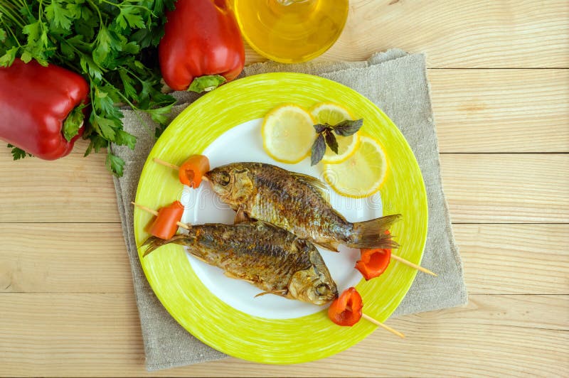 Gebratene Fische u. x28; carp& x29; auf Aufsteckspindeln mit Stücken Pfeffer und Zitrone lizenzfreie stockfotografie
