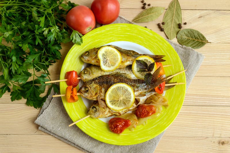 Gebratene Fische u. x28; carp& x29; auf Aufsteckspindeln mit Stückgrünem Pfeffer, sonnengetrockneten Tomaten und Zitrone lizenzfreie stockfotografie
