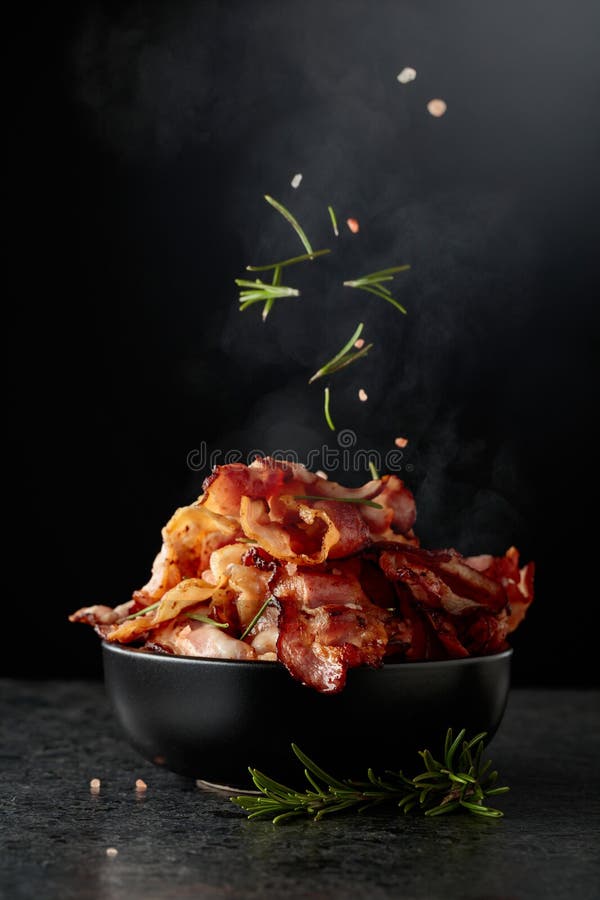 Gebratener Speck in schwarzer Schale mit Rosmarin und rosa Salz stockbilder