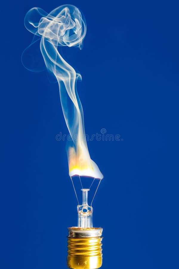 Gebroken gloeilampenbrandwond uit met vlam op blauw stock foto Gebroken gloeilampenbrandwond uit met vlam op blauw stock foto