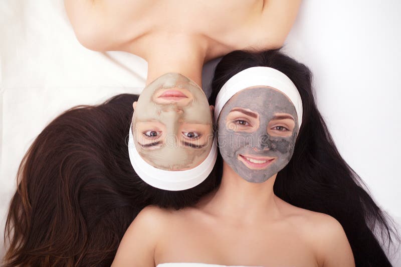 Gebruik van een gezichtsmasker aan gezicht twee jonge vrouwen in een schoonheidssalon stock foto Gebruik van een gezichtsmasker aan gezicht twee jonge vrouwen in een schoonheidssalon stock foto