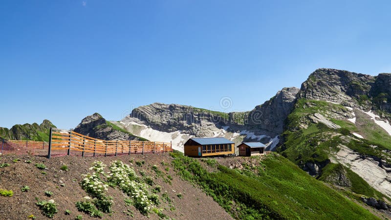 Gebäudebergwachthoch in den Bergen Schnee im Sommer auf den Steigungen der Berge stockbild Gebäudebergwachthoch in den Bergen Schnee im Sommer auf den Steigungen der Berge stockbild