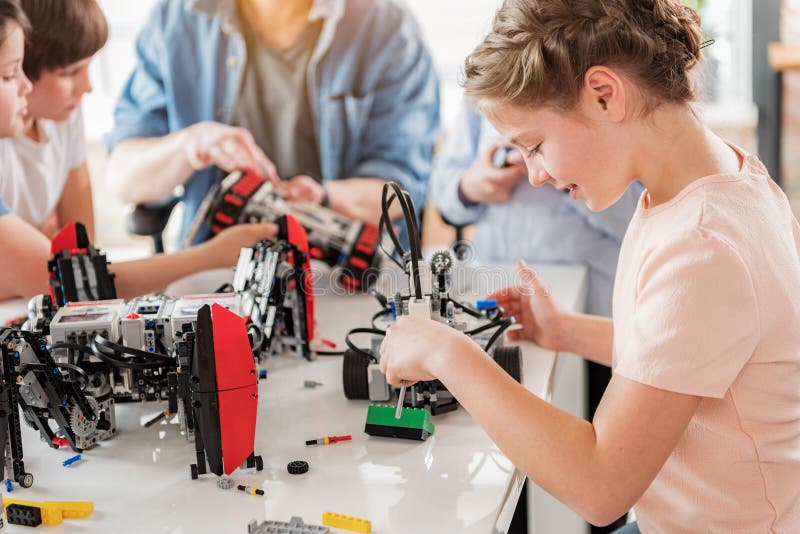 Geconcentreerd glimlachend meisje die technisch stuk speelgoed creëren royalty-vrije stock fotografie Geconcentreerd glimlachend meisje die technisch stuk speelgoed creëren royalty-vrije stock fotografie