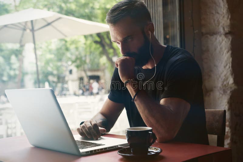 Geconcentreerde Jonge Gebaarde Werkende Laptop van Zakenmanwearing black tshirt Stedelijke Koffie Koffie van de de Lijstkop van d royalty-vrije stock afbeelding Geconcentreerde Jonge Gebaarde Werkende Laptop van Zakenmanwearing black tshirt Stedelijke Koffie Koffie van de de Lijstkop van d royalty-vrije stock afbeelding