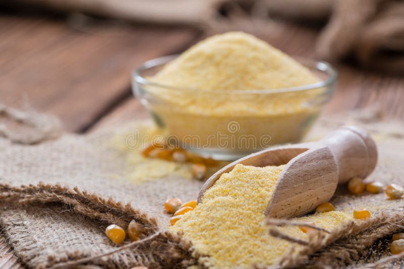 Portion of fresh Cornmeal (close-up shot) on rustic wooden background. Portion of fresh Cornmeal (close-up shot) on rustic wooden background