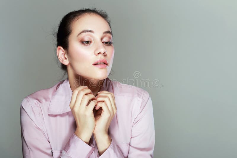 Portrait of a young sad disoriented woman in pink blouse, she looks down. Portrait of a young sad disoriented woman in pink blouse, she looks down