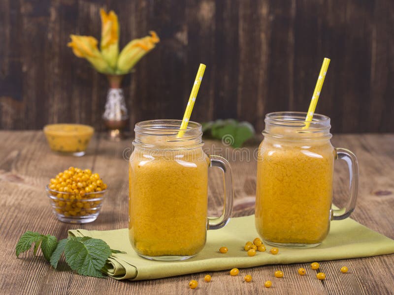 Geel overzees-wegedoorn sap in een glas en rijpe gele duindoorn op een uitstekende houten lijst Bio gezonde voedsel en drank orga stock foto Geel overzees-wegedoorn sap in een glas en rijpe gele duindoorn op een uitstekende houten lijst Bio gezonde voedsel en drank orga stock foto