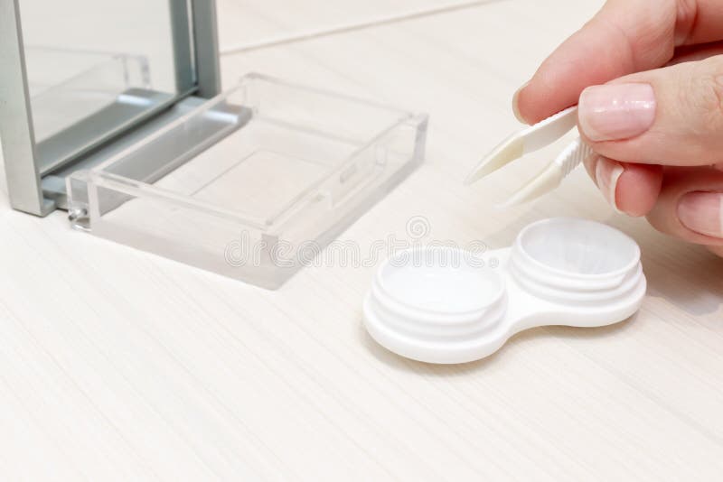 Geerntete weibliche Hände, die Kontaktlinsen aus einem Behälter heraus nehmen lizenzfreies stockbild Geerntete weibliche Hände, die Kontaktlinsen aus einem Behälter heraus nehmen lizenzfreies stockbild