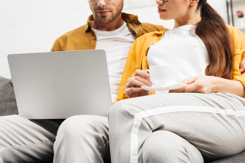 Geernteter Schuss von jungen Paaren mit dem Kaffee- und Laptopsitzen stockfotos