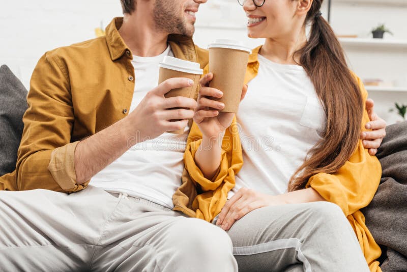 Geernteter Schuss von Paarflirtund klirrenden Papiertasse kaffees lizenzfreies stockfoto