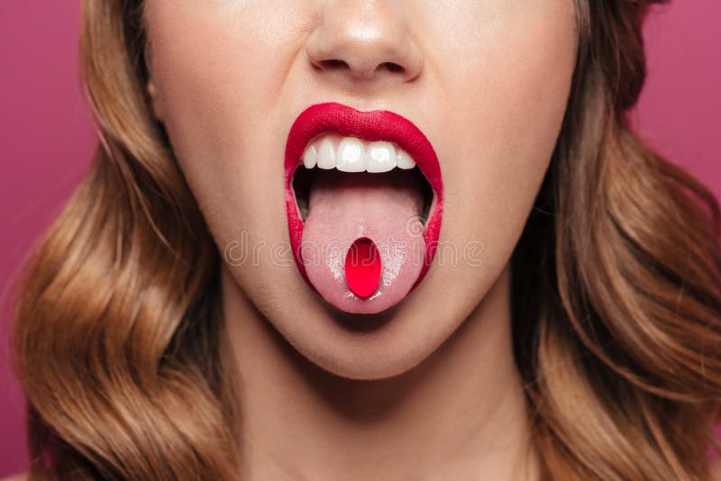 Geerntetes Bild junger Dame mit den roten Lippen, die Pille im Mund halten