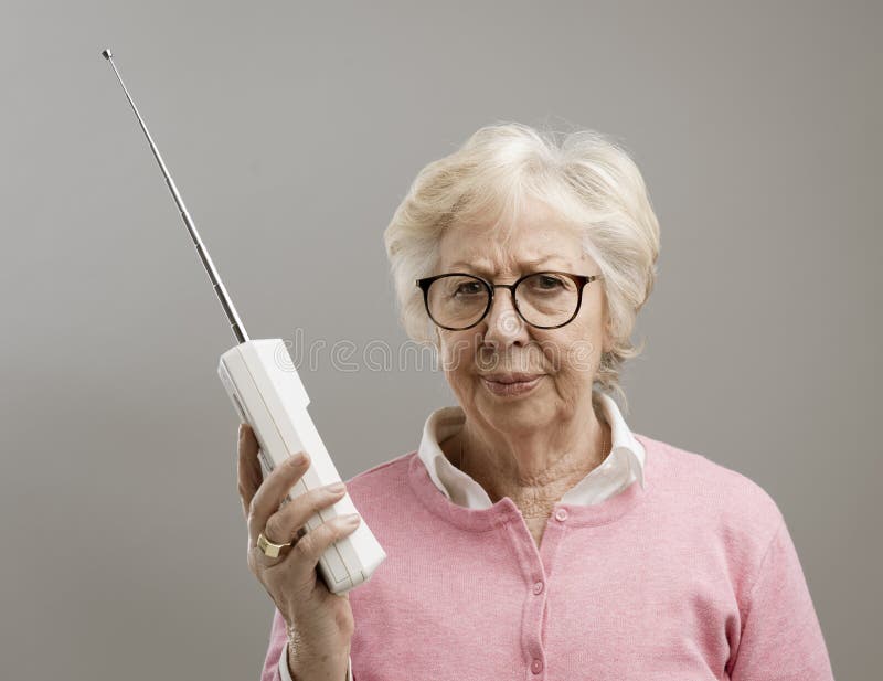 Gefrustreerde hogere vrouw die een oude telefoon met behulp van stock afbeelding Gefrustreerde hogere vrouw die een oude telefoon met behulp van stock afbeelding