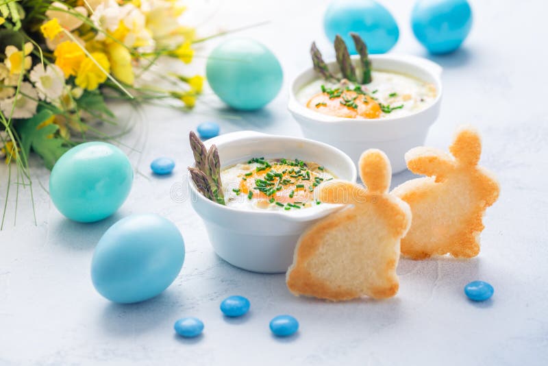 Shirred eggs Oeuf cocotte or baked eggs with green asparagus with Easter toast bunny and eggs. Shirred eggs Oeuf cocotte or baked eggs with green asparagus with Easter toast bunny and eggs