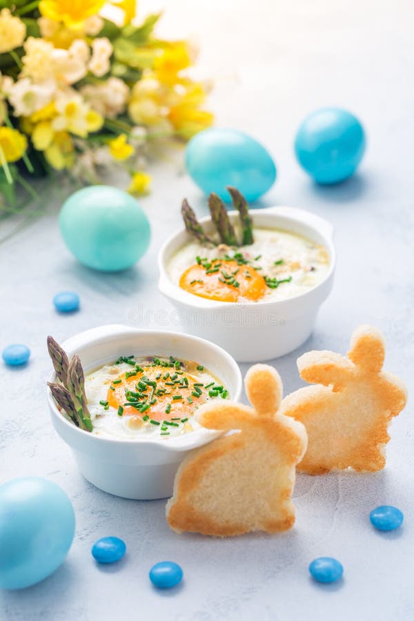 Shirred eggs Oeuf cocotte or baked eggs with green asparagus with Easter toast bunny and eggs. Shirred eggs Oeuf cocotte or baked eggs with green asparagus with Easter toast bunny and eggs