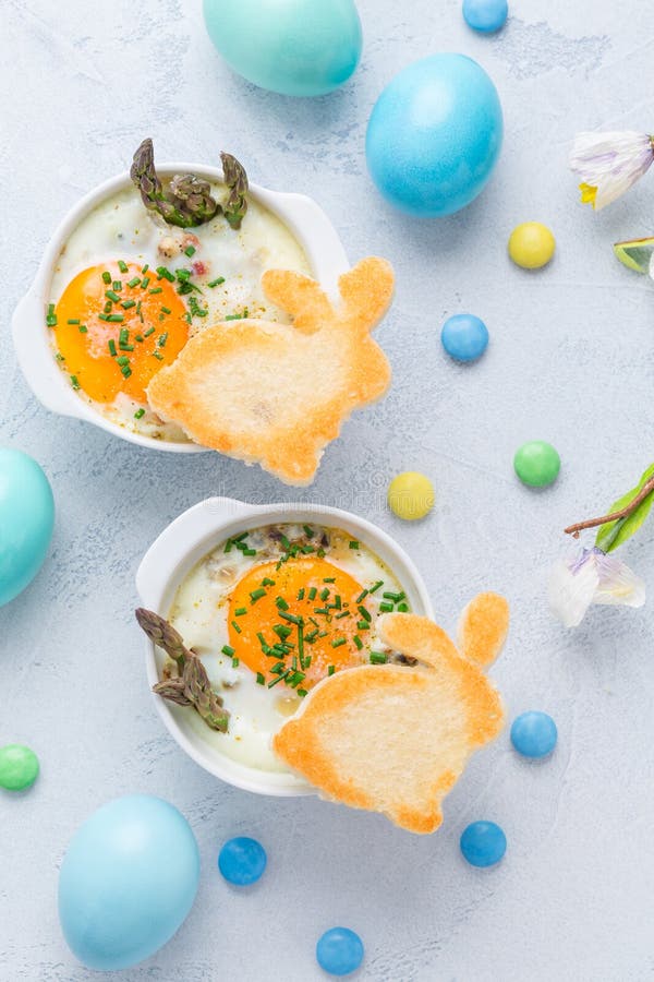 Shirred eggs Oeuf cocotte or baked eggs with green asparagus with Easter toast bunny and eggs. Shirred eggs Oeuf cocotte or baked eggs with green asparagus with Easter toast bunny and eggs