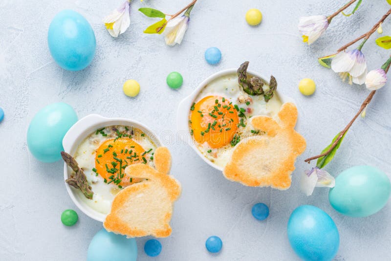 Shirred eggs Oeuf cocotte or baked eggs with green asparagus with Easter toast bunny and eggs. Shirred eggs Oeuf cocotte or baked eggs with green asparagus with Easter toast bunny and eggs