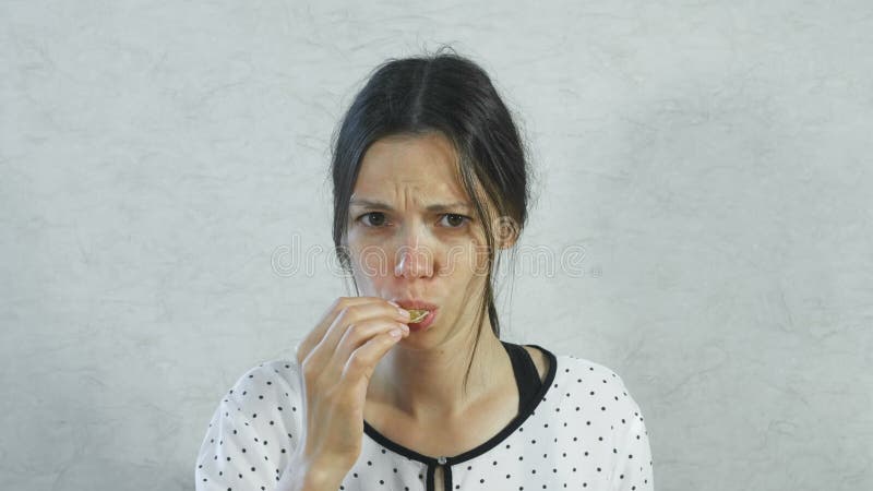 Gefühle vom sauren auf dem Gesicht des Mädchens Brunette Frau, die saure Tangerine und das Zucken isst