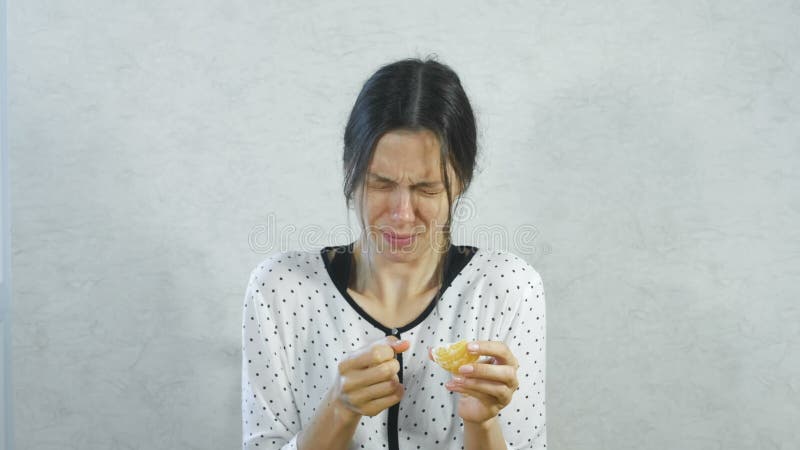 Gefühle vom sauren auf dem Gesicht des Mädchens Brunette Frau, die saure Tangerine und das Zucken isst