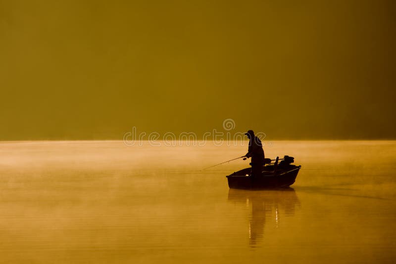 A single angler enjoys fishing from a boat on a beautiful morning. A single angler enjoys fishing from a boat on a beautiful morning.