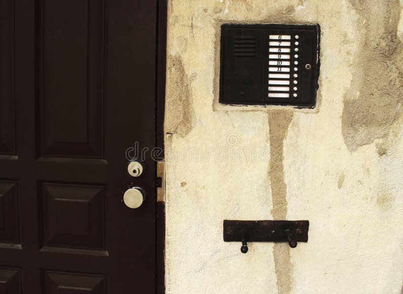 Gegensprechanlage mit Nummern für alte Putzmauer bei schwarzer Eingangstür stockbild Gegensprechanlage mit Nummern für alte Putzmauer bei schwarzer Eingangstür stockbild