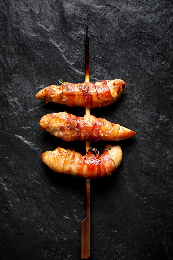Gegrillte Aufsteckspindeln des Hühnerzarten lendenstücks eingewickelt mit Speck auf einem schwarzen Hintergrund stockfotos Gegrillte Aufsteckspindeln des Hühnerzarten lendenstücks eingewickelt mit Speck auf einem schwarzen Hintergrund stockfotos
