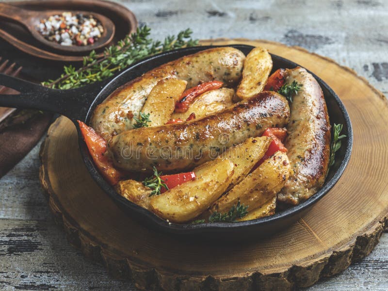 Gegrillte H? hnerw? rste mit gebratenen Kartoffeln und Pfeffern in einem Eisenstein lizenzfreie stockfotografie