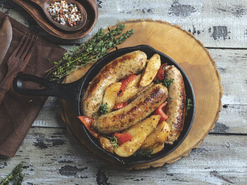 Gegrillte H? hnerw? rste mit gebratenen Kartoffeln und Pfeffern in einem Eisenstein lizenzfreie stockfotografie