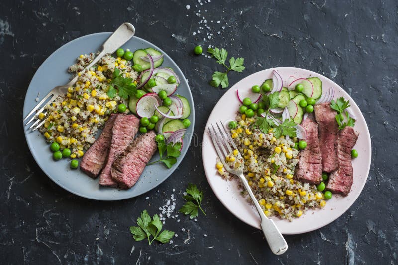 Grilled beef steak and quinoa corn mexican salad on dark background, top view. Delicious healthy balanced food concept. Grilled beef steak and quinoa corn mexican salad on dark background, top view. Delicious healthy balanced food concept